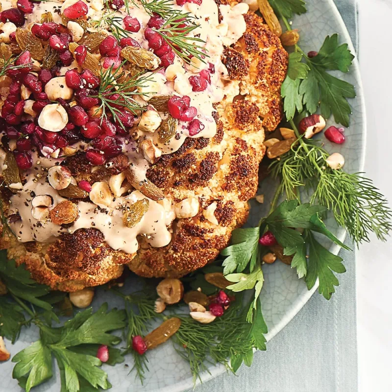Whole Roasted Cauliflower with Pomegranate Tahini Sauce, Raisins, and Hazelnuts
